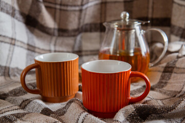 two cups and a teapot with tea on a beige blanket
