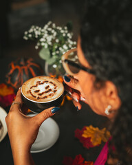 Girl holding a Halloween cappuccino coffee with a scary spooky pumpkin latte art and decorations
