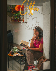 Girl reading book through window in Halloween with scary spooky pumpkin decorations