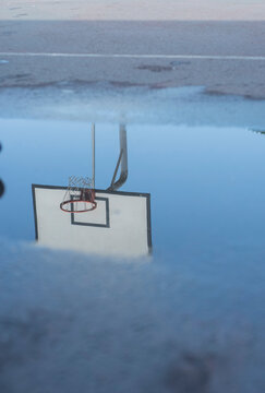 Reflection of a basketball ring in a puddle after the rain.