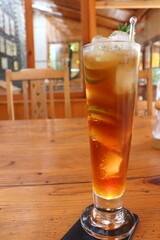 Long island iced tea cocktail. Typically made with vodka, tequila, light rum, triple sec, gin, and a splash of cola. Garnish with lemon spiral. Serve with straw. moody background. copy space