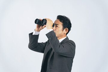 双眼鏡で遠くを見る中年ビジネスマン
