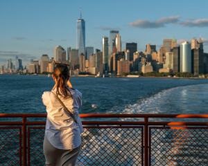 Woman looking around from Staten island ferry and taking photo about Lower Manhattan in New York city. - obrazy, fototapety, plakaty