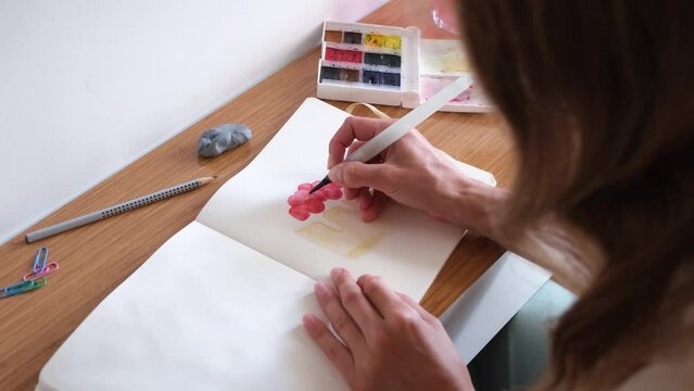 closeup of unrecognizable woman drawing with watercolor paint, making sketch of a cake