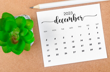 The December 2023 Monthly calendar for 2023 year with wooden pencil on wooden table.