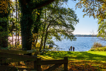 Eine Familie an einem Herbstlichen See beim Spaziergang Schild unbewachte Badestelle