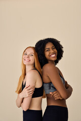 Two happy diverse fit women, African and European young sporty gen z girls friends models wearing...