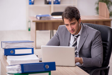 Young male employee unhappy with excessive work in the office