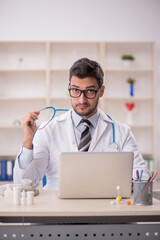 Young male doctor holding phonendoscope in the clinic