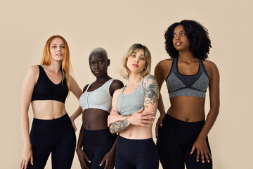 Cool fit sporty diverse young women wearing sportswear standing at beige background. Multicultural...