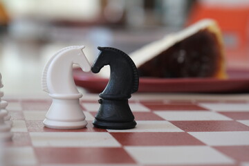 white and black knight facing each other in chess. Black and white chess knight standing side by...