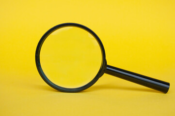 Blank magnifying glass on yellow cover background. Copy space.