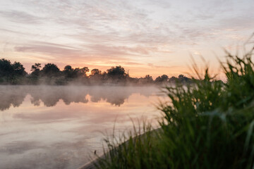 Fototapeta na wymiar Beautiful landscape with a river and reflection, thick fog at dawn. Lake in the early morning in thick fog
