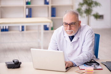 Old male doctor working in the clinic