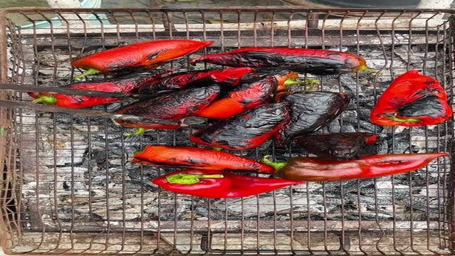 Red bell peppers being roasted on outdoor grill