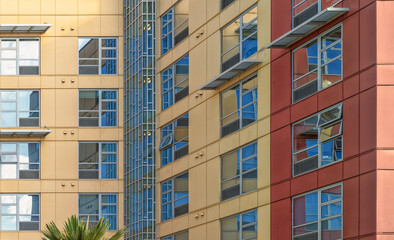 Fototapeta premium Closeup View of a Red and Yellow Building Exterior Corner with Windows and Reflections.