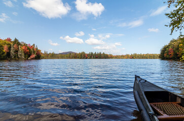 Canoe on Adirondack lake in St Regis Wilderness with peak fall foliage on a peaceful calm morning