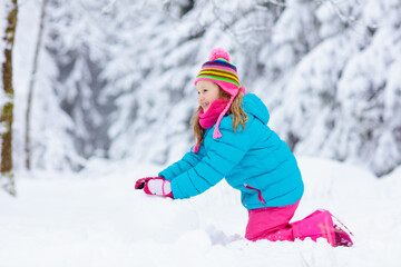 Fototapeta na wymiar Child making snowman. Kids play in snow in winter