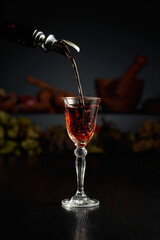 Brown herbal liquor or rum is poured from a vintage bottle.