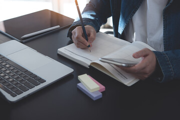 Event planner timetable agenda plan on year 2024 schedule event. Business woman checking planner on mobile phone, scheduling on calendar planner, laptop computer on office table