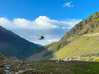 a helicopter flying above the mountain hills of keadrnath