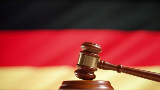 A judge gavel with a flag of Germany on background. Close up of wooden hammer and legal lawyer books or codex. Sentence law or legal system and jurisprudence or court concept.