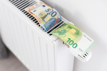 Banknotes for a heating radiator in the house. Central heating in the apartment. Economical consumption of resources. - obrazy, fototapety, plakaty