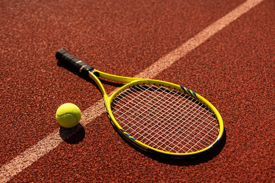 Play tennis. Close-up of tennis racket and tennis ball laying on the court 