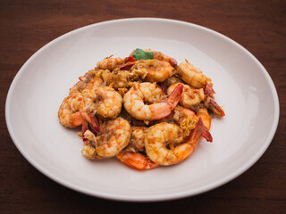Stir fried shrimps with garlic and white pepper in plate on wooden table. Thai Food