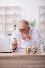 Old male doctor suggesting pills in the clinic