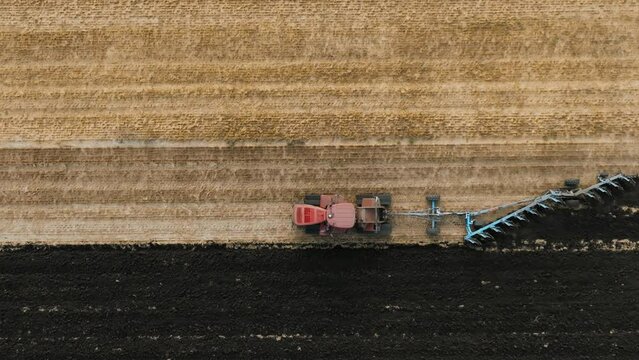 Big red tractor on on rubber tracks, Pulling productive reverse plow on Field. Preparation soil for Planting new crops, Agriculture. Aerial view of tractor field plowing. slow motion video