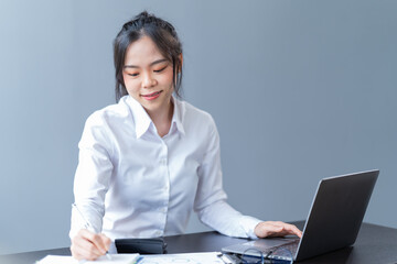 Smiling female student browsing laptop and tablet sitting at table holding coffee cup with papers and books while doing homework in cozy cafe