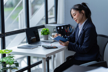 Portrait of a happy beautiful Asian businesswoman. Working with a laptop and Mobilphone in a...