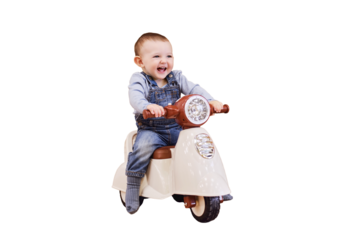 Happy baby boy rides a plastic children motorcycle in the playroom, isolated on a white background. A smiling child drives a moped toy, isolated on a white background. Kid age one year