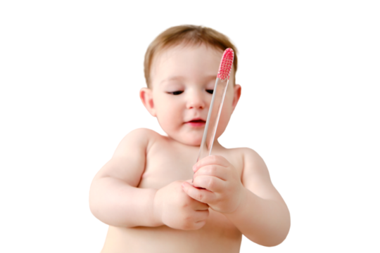 Child cleans his mouth with a toothbrush in his hands, isolated on a white background. Happy toddler baby learns to brush her teeth while lying on her home bed. Kid aged one year