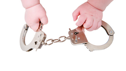 Baby hand and handcuffs, close-up, isolated on a white background. Children fingers and an object on a white background
