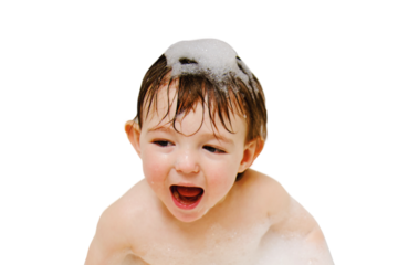 A happy child is playing with toys while sitting in a white homemade bathtub, isolated on white background. Little toddler baby boy bathes in a bubble bath. Kid aged one year six months