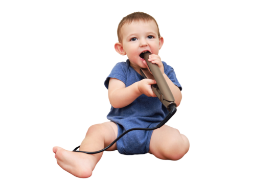 Child boy chewing on the electric wire of a curling iron, copy space, isolated on a white background. Toddler baby plays with hot curling tongs at the electrical outlet. Kid age one year