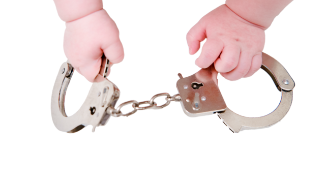 Baby hand and handcuffs, close-up, isolated on a white background. Children fingers and an object on a white background