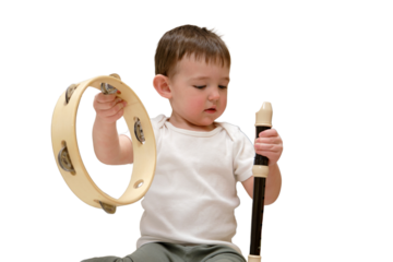 Toddler baby plays the flute sitting on the floor in the children's room. Child boy playing musical instruments. Kid aged one year eight months