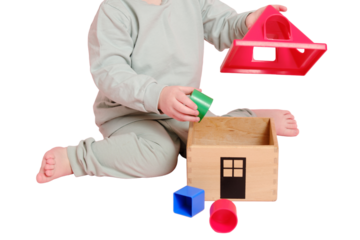 Happy toddler baby plays sorter with geometric shapes on studio, isolated on white background. Child boy plays educational toys, isolated on white background. Kid age one year eight months