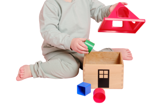 Happy toddler baby plays sorter with geometric shapes on studio, isolated on white background. Child boy plays educational toys, isolated on white background. Kid age one year eight months