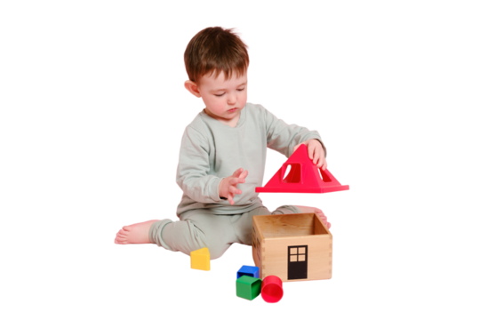 Happy toddler baby plays sorter with geometric shapes on studio, isolated on white background. Child boy plays educational toys. Kid age one year eight months, full height