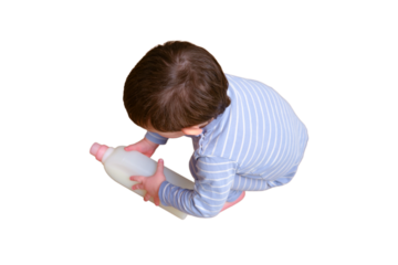 Toddler baby plays with household chemicals and detergent from the closet, isolated on white background. Child boy with detergent bottle in home living room. Kid age one year nine months