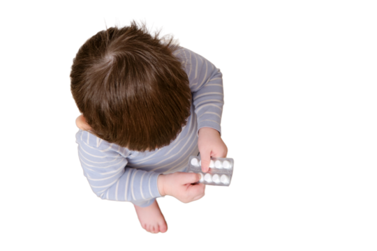 Toddler baby opened the cabinet drawer with pills and medicine, isolated on white background. Child boy holding a pack of pills in the home living room. Kid age one year nine months