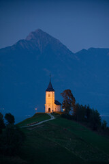 Illuminated The Church of St. Primoz and Felicijan in the village of Jamnik in the Slovenian Alps at night. Vertical view