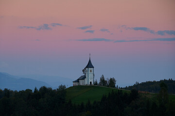 Fototapeta premium Twilight over The Church of St. Primoz and Felicijan in the village of Jamnik in the Slovenian Alps. Beautiful colorful sky.