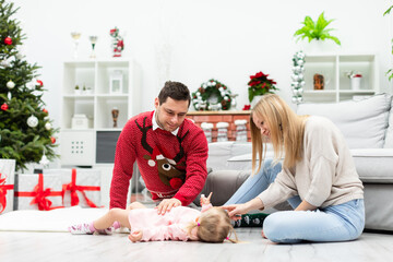 Family plays together while sitting on the floor near the decorated Christmas tree
