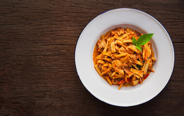 Top view of spicy stir fried pork with bamboo shoot in plate on wooden background. Thai Food
