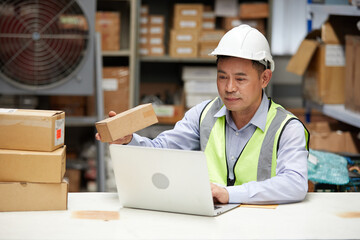 factory worker looking at cardboard box packaging in the warehouse storage